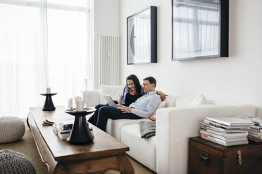 Mann und Frau sitzen mit Laptop auf dem Sofa - FOLF04535