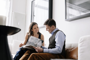 Couple sitting on sofa and reading book - FOLF04563