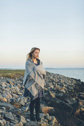 Junge Frau in einen Schal gehüllt mit Blick aufs Meer - FOLF04672