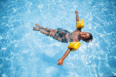 Boy wearing water wings floating in a pool - FOLF04752