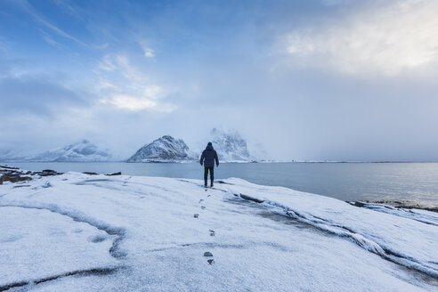 Man standing in snow looking out to sea - FOLF04762