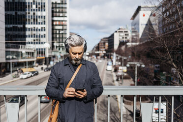 Mann mit Smartphone auf der Straße in Stockholm, Schweden - FOLF04853