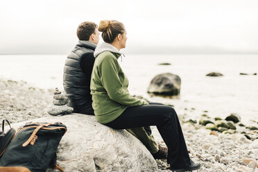 Couple sitting on rock on coastline - FOLF04864
