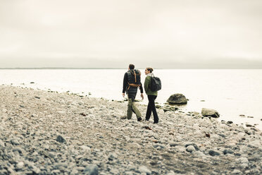 Rear view of couple walking along rocky coastline - FOLF04872