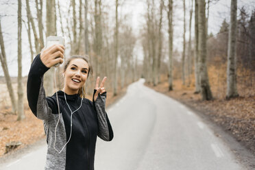 Junge Frau nimmt Selfie auf Landstraße - FOLF04892