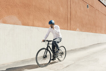 Mann telefoniert beim Radfahren mit seinem Smartphone - FOLF04919