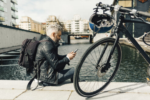 Mann am Smartphone mit Fahrrad in Stockholm, Schweden - FOLF04927