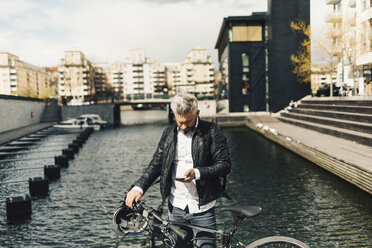 Man on smart phone with bicycle in Stockholm, Sweden - FOLF04929
