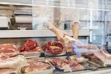 Butcher arranging meat on display - FOLF04935