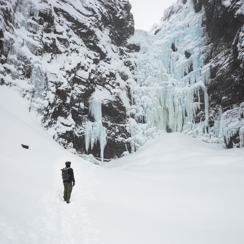 Mann neben einem gefrorenen Wasserfall im Fulufjallet-Nationalpark, Schweden, lizenzfreies Stockfoto