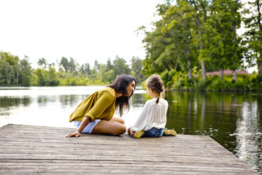 Mother and daughter on pier beside lake - FOLF05088