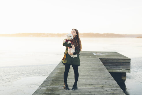 Junge Frau auf dem Pier mit ihrem Hund im Winter - FOLF05113