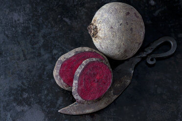 Ganze und geschnittene Rote Bete und ein altes Messer auf dunklem Metall - CSF29015