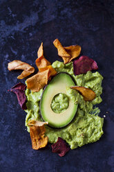 Guacamole, slice of avocado and vegetable chips on dark ground - CSF29030