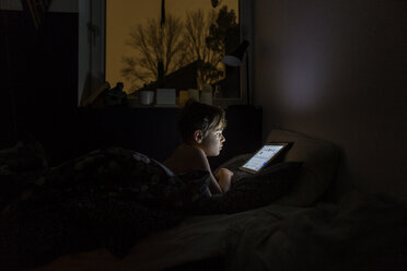 Boy playing with tablet PC in bed at night - FOLF05203