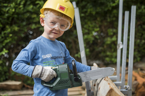 Portrait of boy with toy saw pretending to saw wood - PAF01785