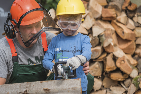 Vater und Sohn sägen gemeinsam Holz, lizenzfreies Stockfoto