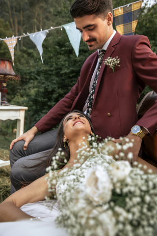 Glückliche Braut lächelnd und liegend mit Bräutigam auf dem Feld, lizenzfreies Stockfoto