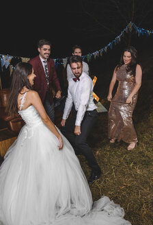 Happy bride dancing and having fun with her friends on a night field party - DAPF00941