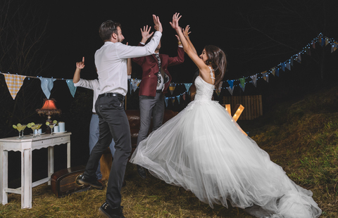 Glückliche Braut springt und gibt high five mit ihren Freunden auf einer Nacht Feld Partei mit Freunden, lizenzfreies Stockfoto