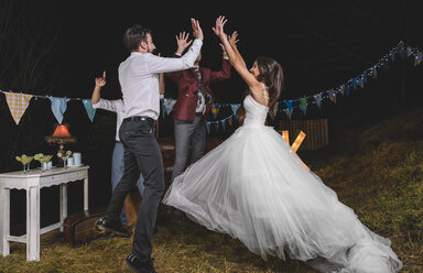 Glückliche Braut springt und gibt high five mit ihren Freunden auf einer Nacht Feld Partei mit Freunden - DAPF00944