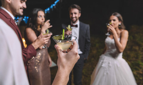 Glückliche Freunde trinken Cocktails auf einer nächtlichen Hochzeitsfeier, lizenzfreies Stockfoto