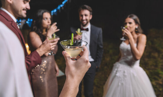 Glückliche Freunde trinken Cocktails auf einer nächtlichen Hochzeitsfeier - DAPF00947