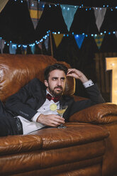 Nachdenklicher Mann im Anzug auf dem Sofa liegend auf einer Nachtparty im Freien - DAPF00952