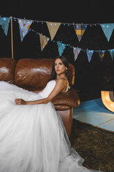 Serious bride lying on sofa on a night field party - DAPF00957
