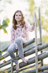 Porträt eines lächelnden Mädchens, das auf einem Zaun sitzt - FOLF05578