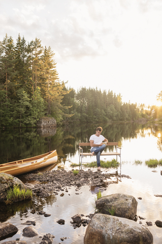 Man sitting on bench in middle of lake stock photo