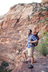 Smiling man standing on rocky path against mountain - CAVF31170