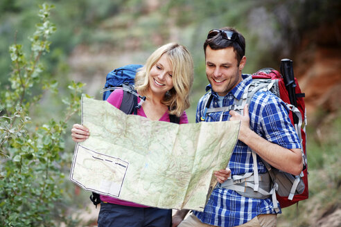 Glückliches Paar prüft Karte beim Wandern - CAVF31175