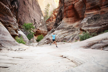 Woman running on field against mountains - CAVF31178