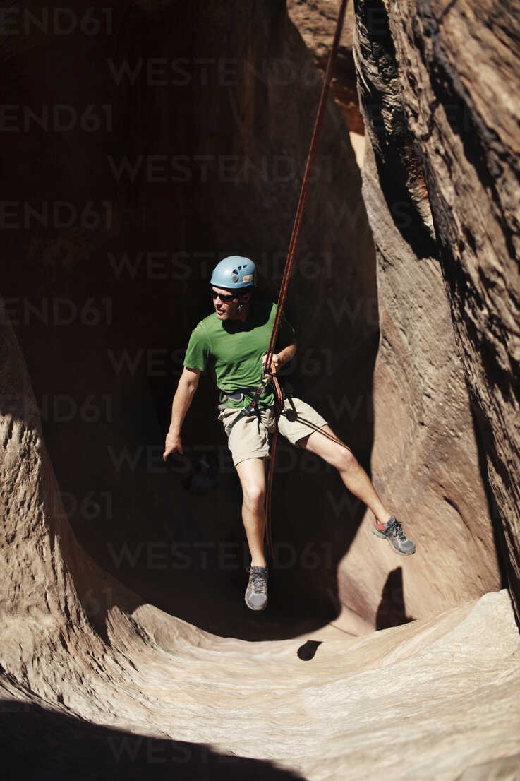 High angle view of man hanging on rope against rock formation stock photo