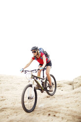 Woman riding bicycle on mountain against clear sky - CAVF31206