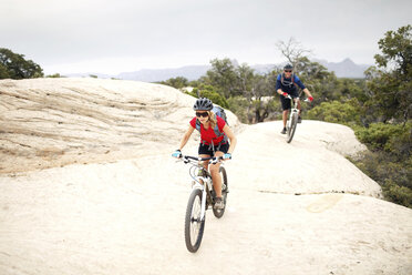 Ein Paar fährt mit dem Fahrrad auf einem Felsen gegen den klaren Himmel - CAVF31208