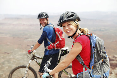 Portrait of couple smiling while standing with bicycles on cliff - CAVF31215