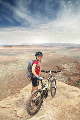 Portrait of woman standing with bicycle on cliff - CAVF31218