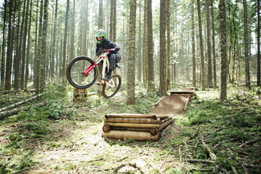 Man doing stunt with bicycle amidst trees - CAVF31244