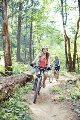 Paar fährt Fahrrad auf unbefestigtem Weg im Wald - CAVF31282