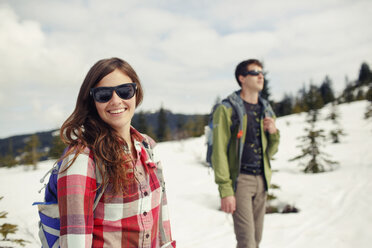 Glückliche Freunde wandern auf einem schneebedeckten Feld gegen einen bewölkten Himmel - CAVF31310