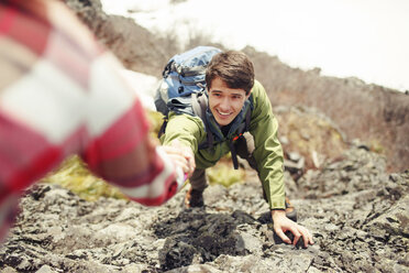 Cropped image of woman assisting male friend in climbing mountain - CAVF31316