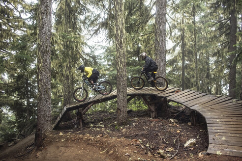 Freunde fahren mit dem Mountainbike auf der Promenade im Wald - CAVF31325