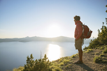 Hiker with backpack standing on mountain at Crater Lake National Park during sunny day - CAVF31362