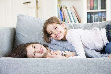 Portrait of two happy sisters cuddling on the couch - LVF06839