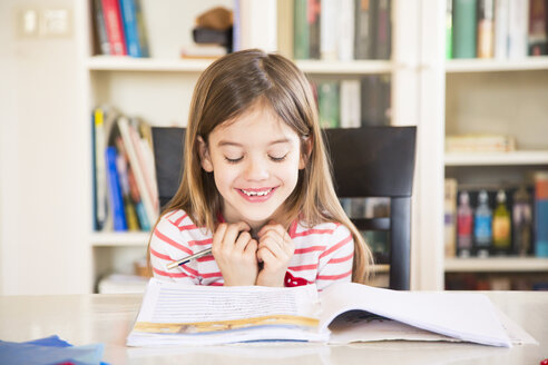 Portrait of happy little girl doing homework - LVF06841