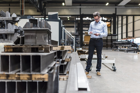 Mann mit Tablet in einer Fabrikhalle stehend - DIGF03547