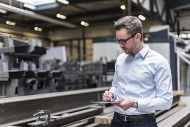 Man using tablet on factory shop floor - DIGF03548