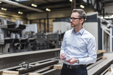 Man using tablet on factory shop floor - DIGF03549